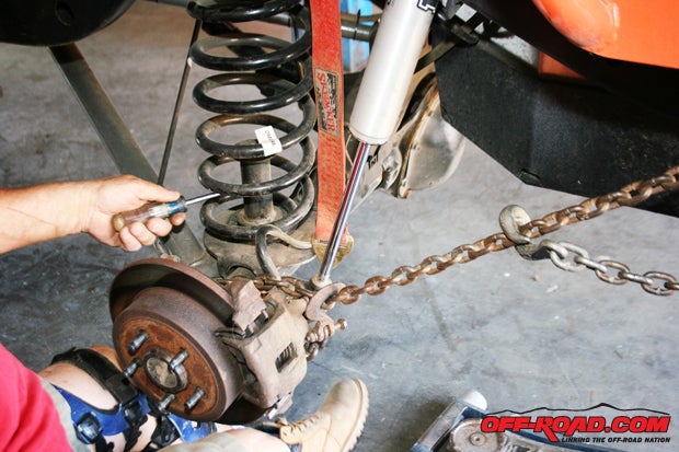 In order to remove the coil spring, the bottom bump stop must be unscrewed from the spring pad.