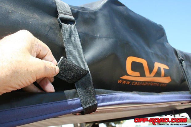 To set up the tent, first remove the straps securing the heavy-duty travel cover. The straps are secured with lengths of Velcro after passing through a cleat mounted to the floorboard.